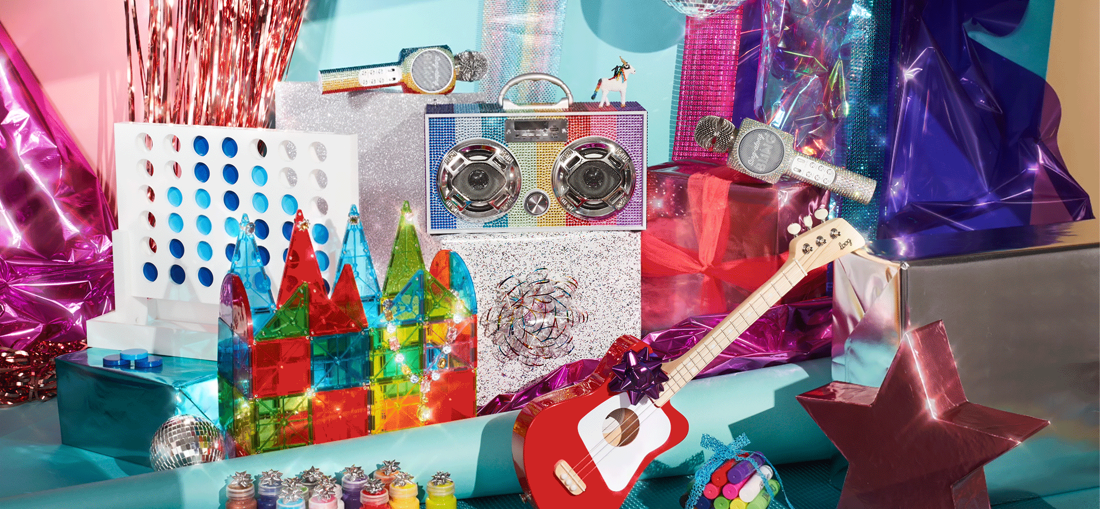 Holiday still life image of a toy guitar, Magna-tiles, karaoke microphone, boom box and connect four game,