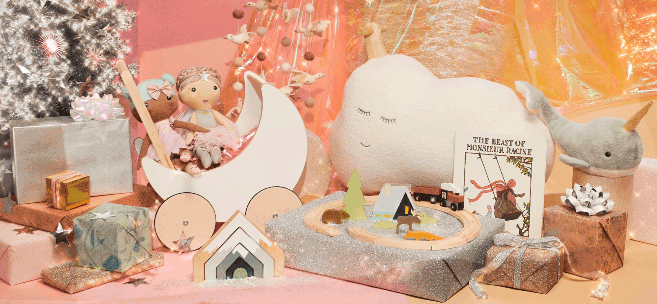 Holiday still life image with a silver Christmas tree, toy dolls, a ride-on cloud, a plush narwal a moon shaped stroller, train track pieces and presents