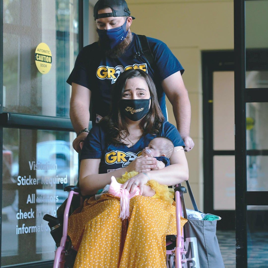 Britni's husband, Mike, pushing her and Gracie in a wheel chair in the hospital; A team of NICU doctors and nurses wearing "Gracie Strong" t-shirts