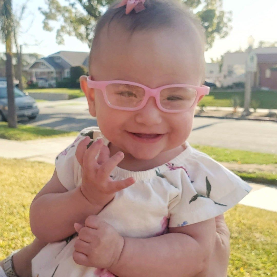 Smiling baby Gracie wearing pink glasses; Gracie and Britni