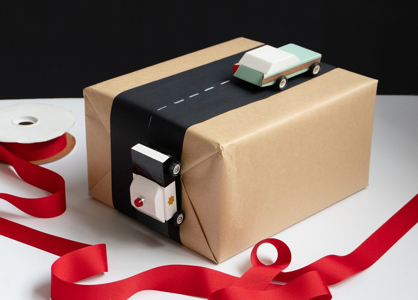 using paper and wooden cars to create a road on a present  