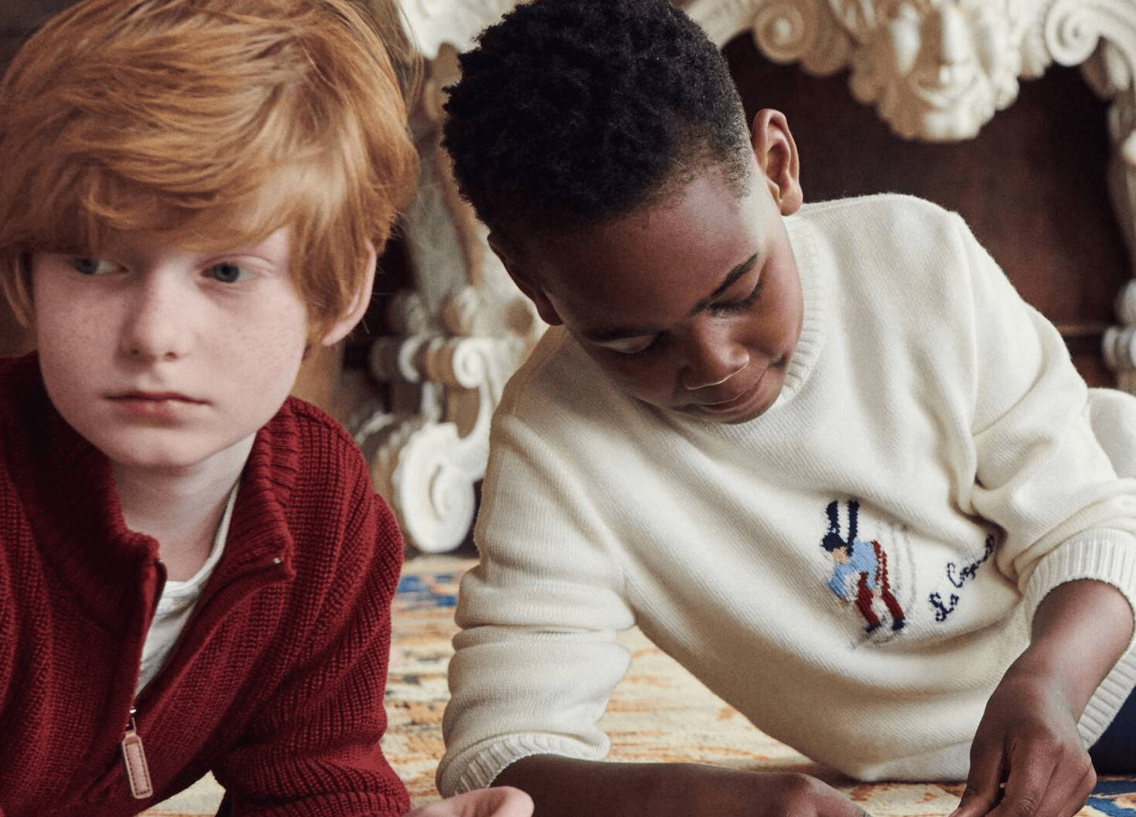 Two boys wear holiday sweaters.