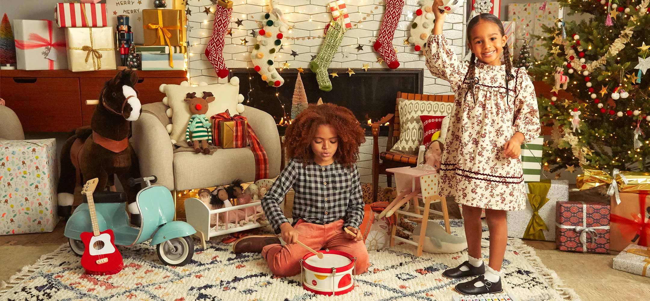 photo of a girl and boy standing a room decorated with holiday decor and a christmas tree.