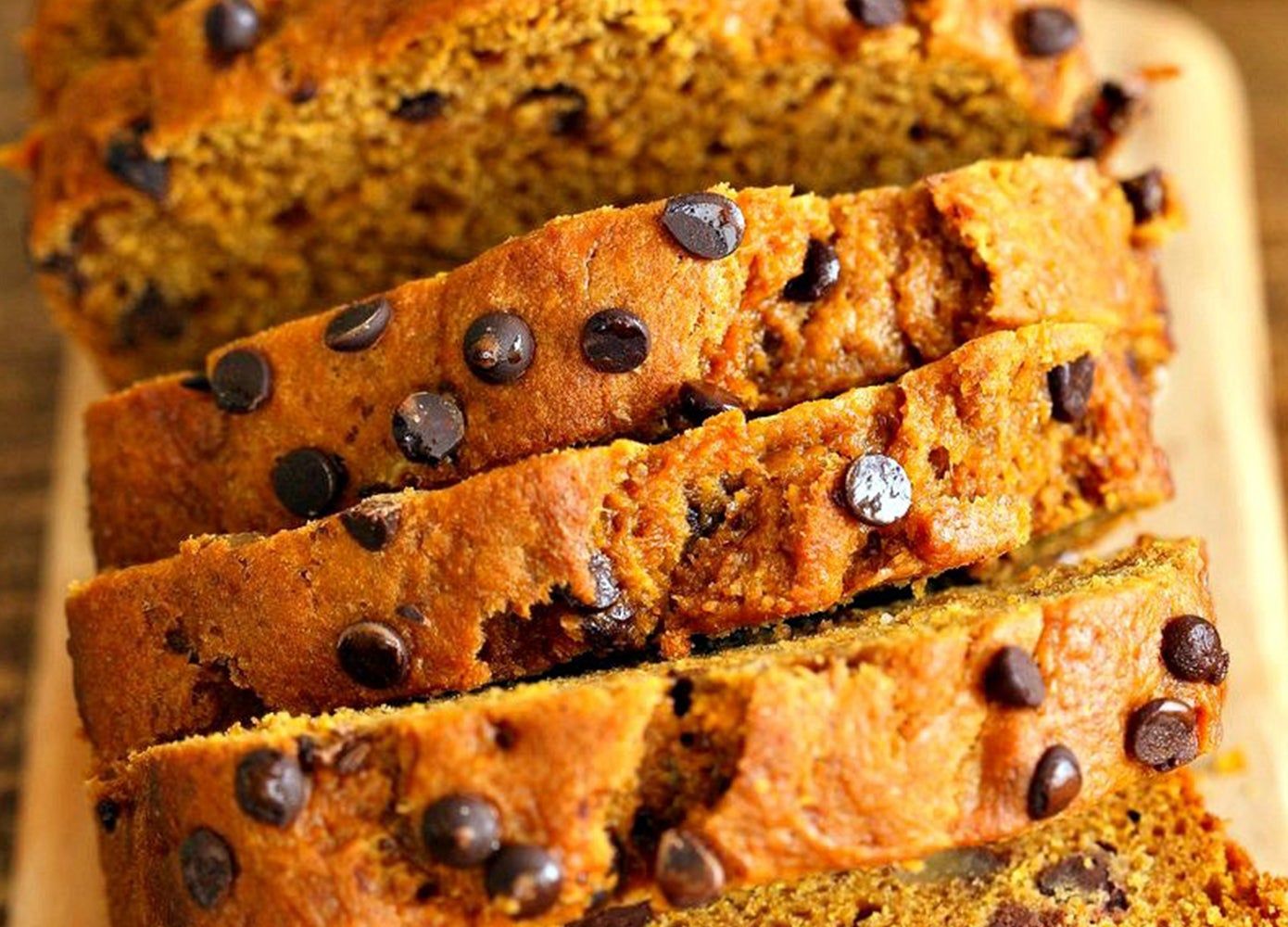 Overhead photo of a loaf of pumpkin bread with chocolate chips, sliced into five slices