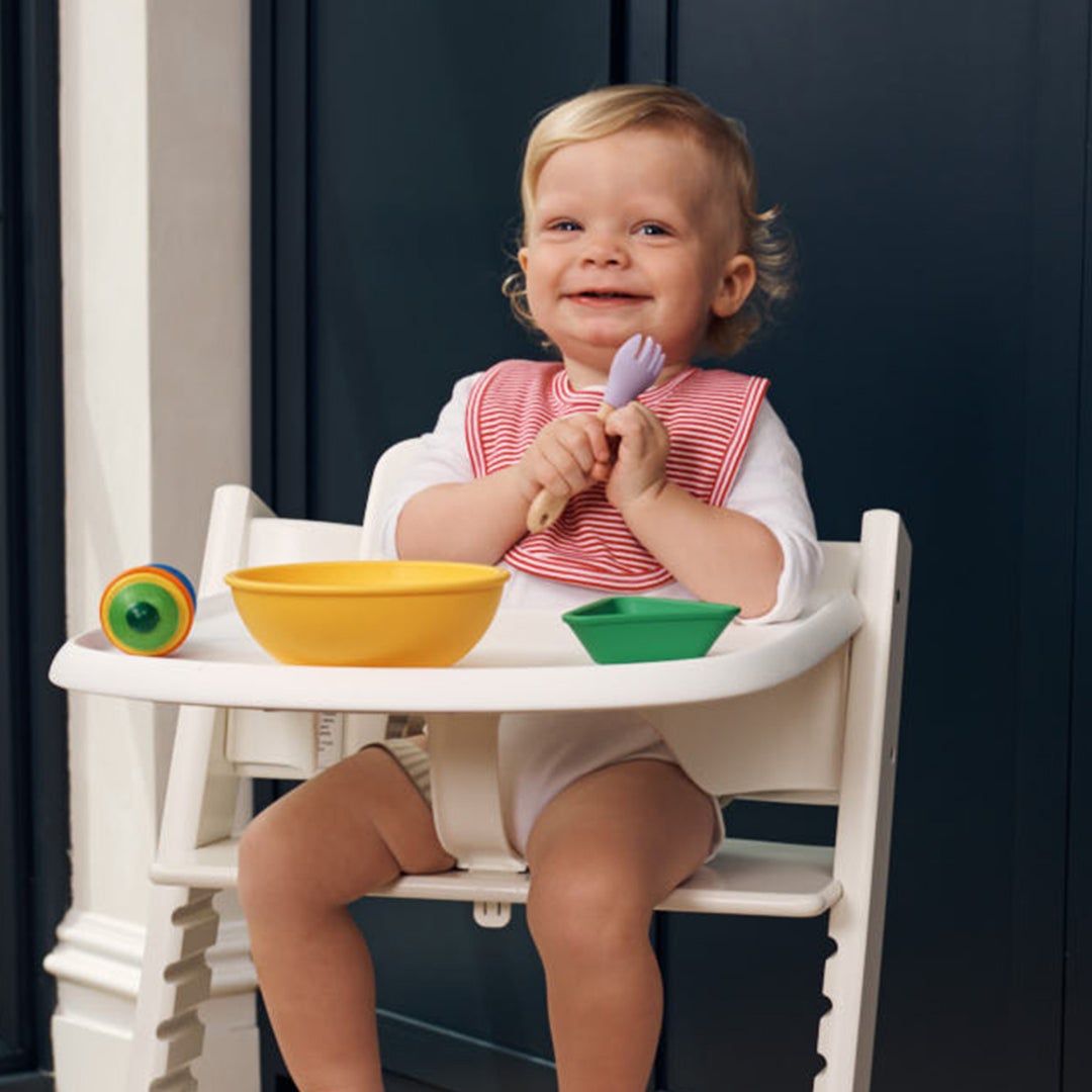 photo of a toddler sitting in a white high chair in a kitchen