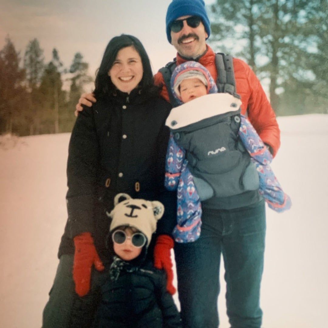 mother, father, and toddler bundled up in the snow