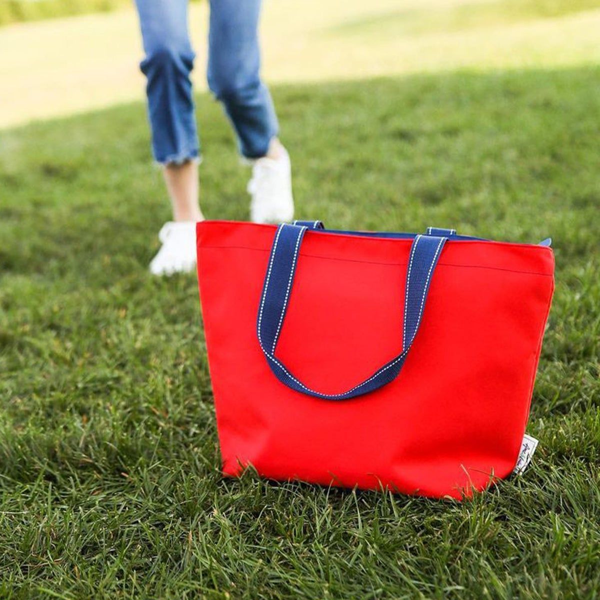 A red tote on green grass with a person in the background
