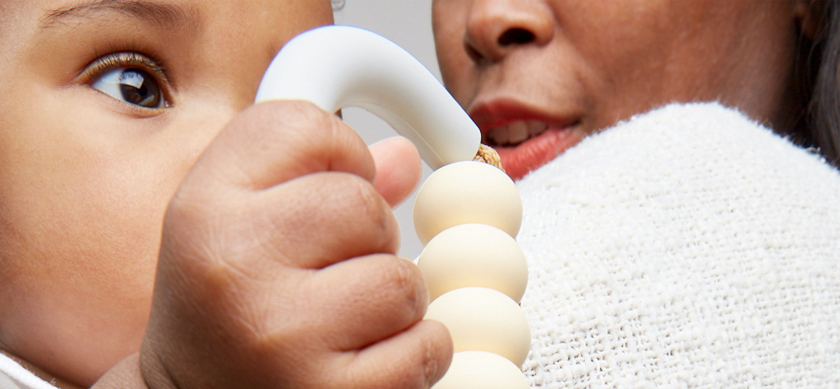Mother holding baby with teething toy.