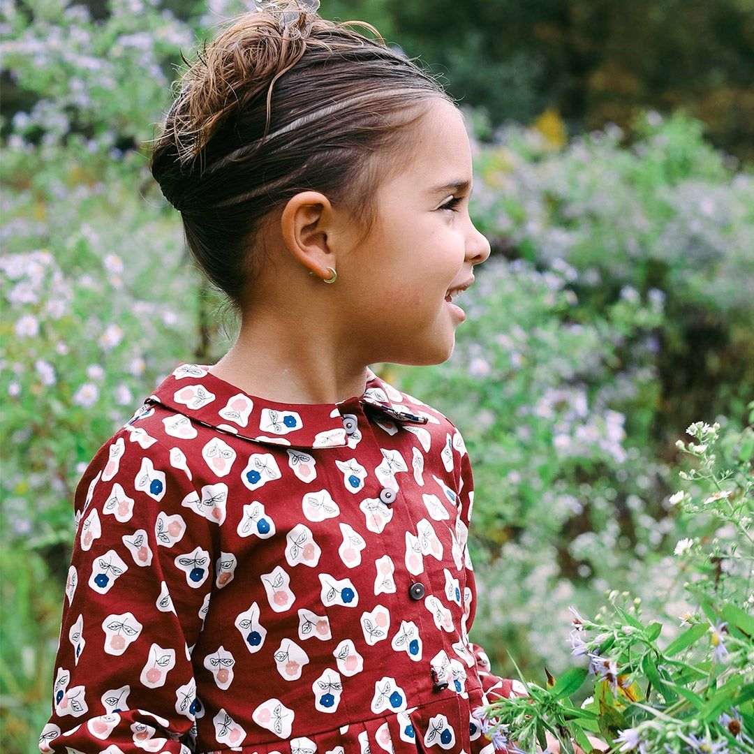 Bela's daughter outside, smiling and surrounded by wildflowers