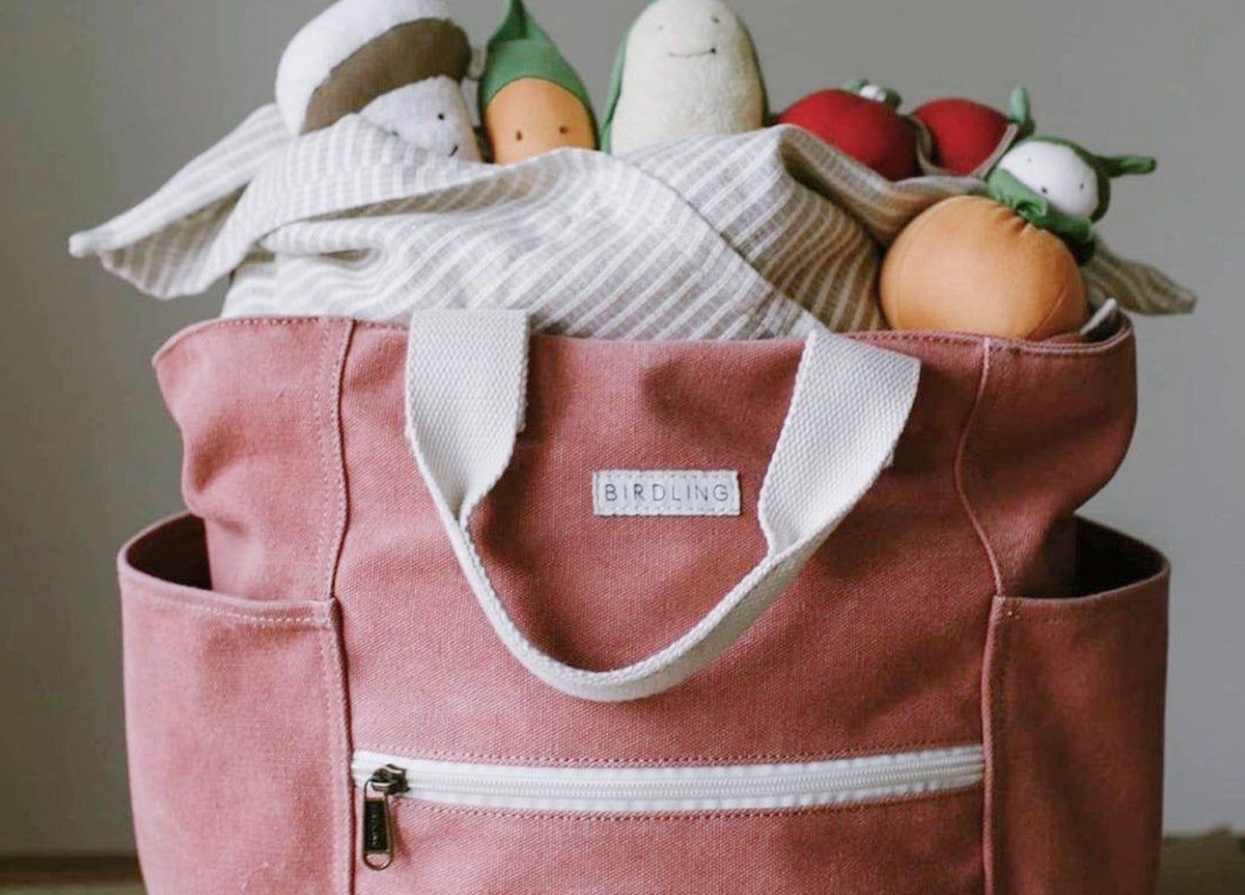 A red canvas tote stuffed with fake fruit