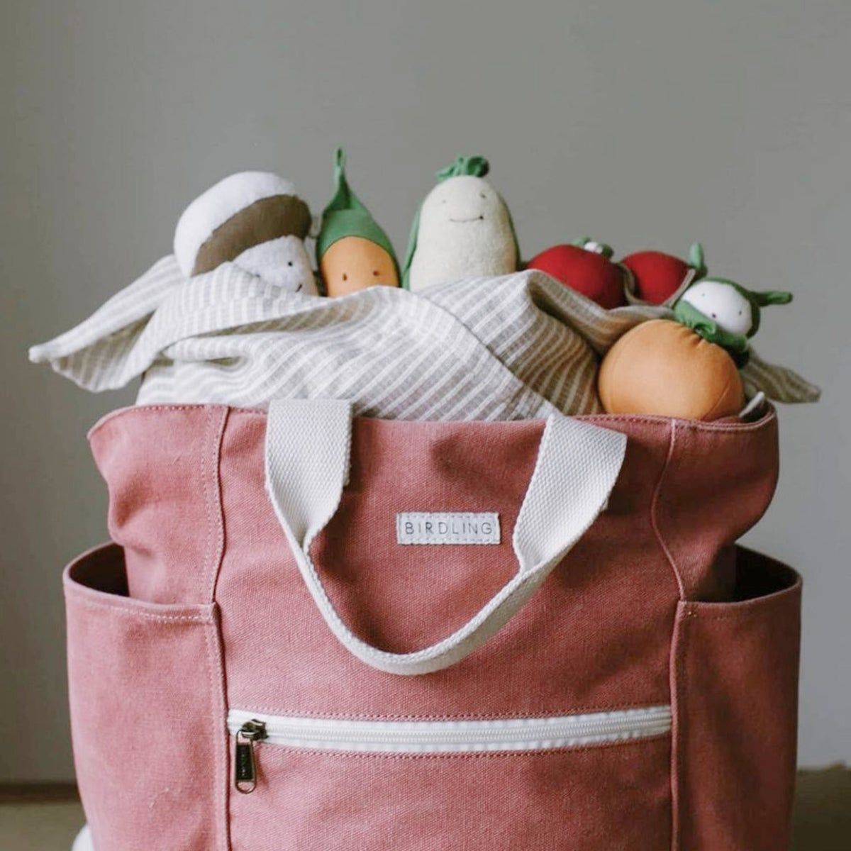 A red canvas tote stuffed with fake fruit