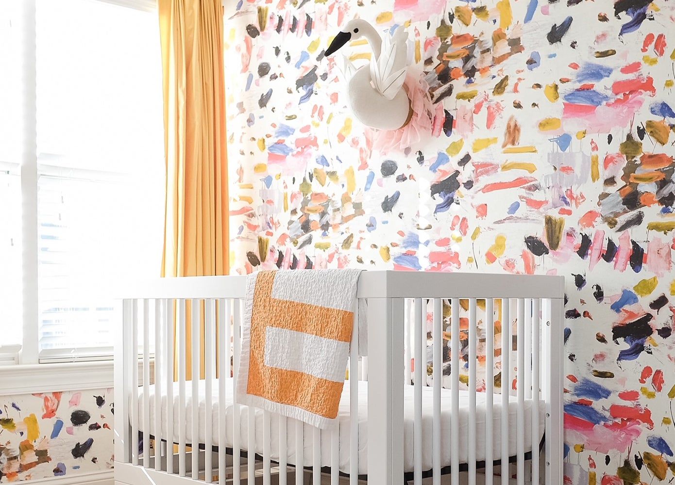 a white crib against a colorful wallpaper wall