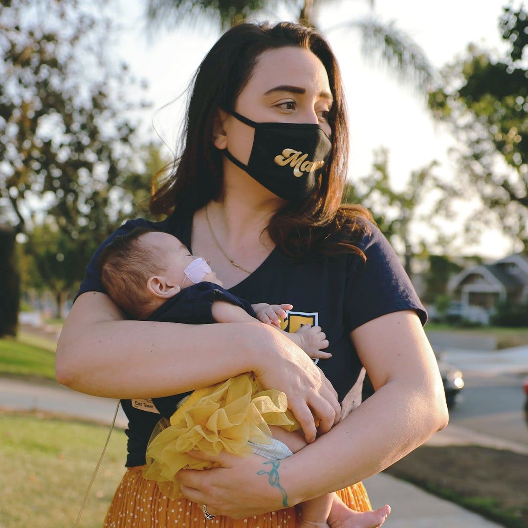 Britni Soto holding her baby Gracie while wearing a mask