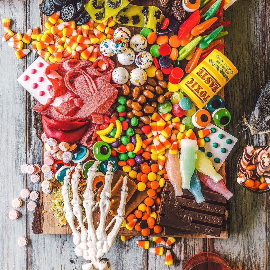 a wood board covered with candy and a toy skeleton hand reaching for candy