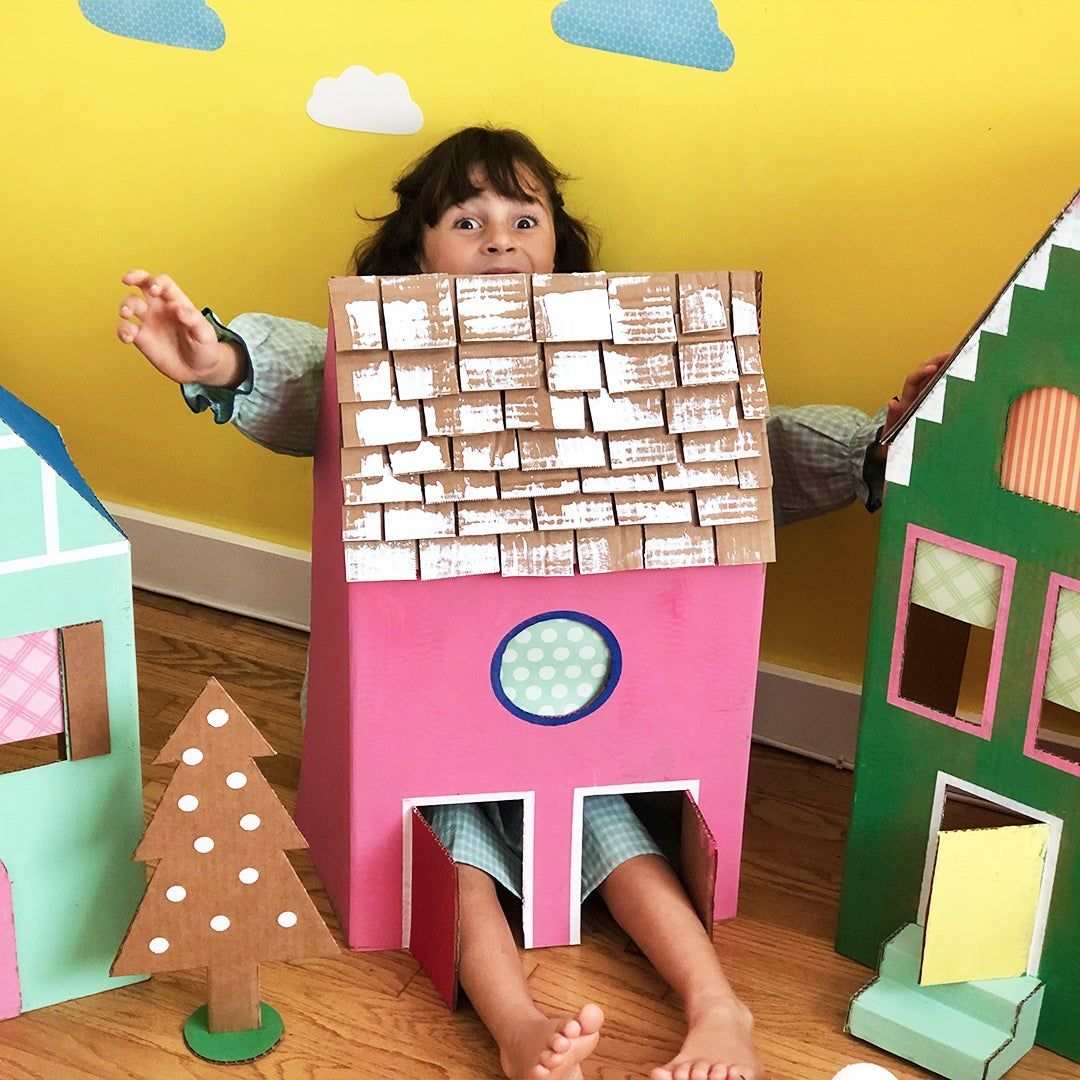a little girl inside a colorful cardboard box house