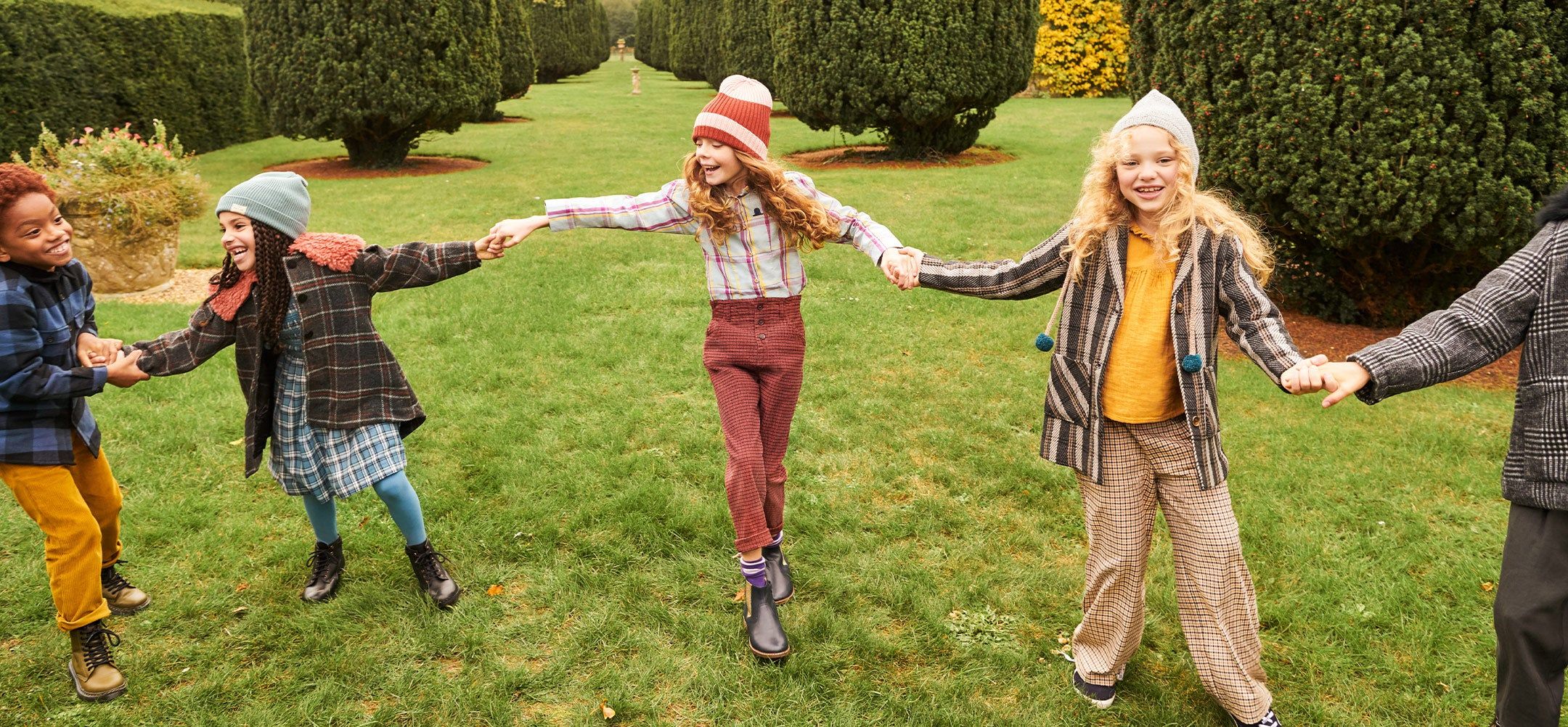 Five children holding hands in a beautiful winter garden