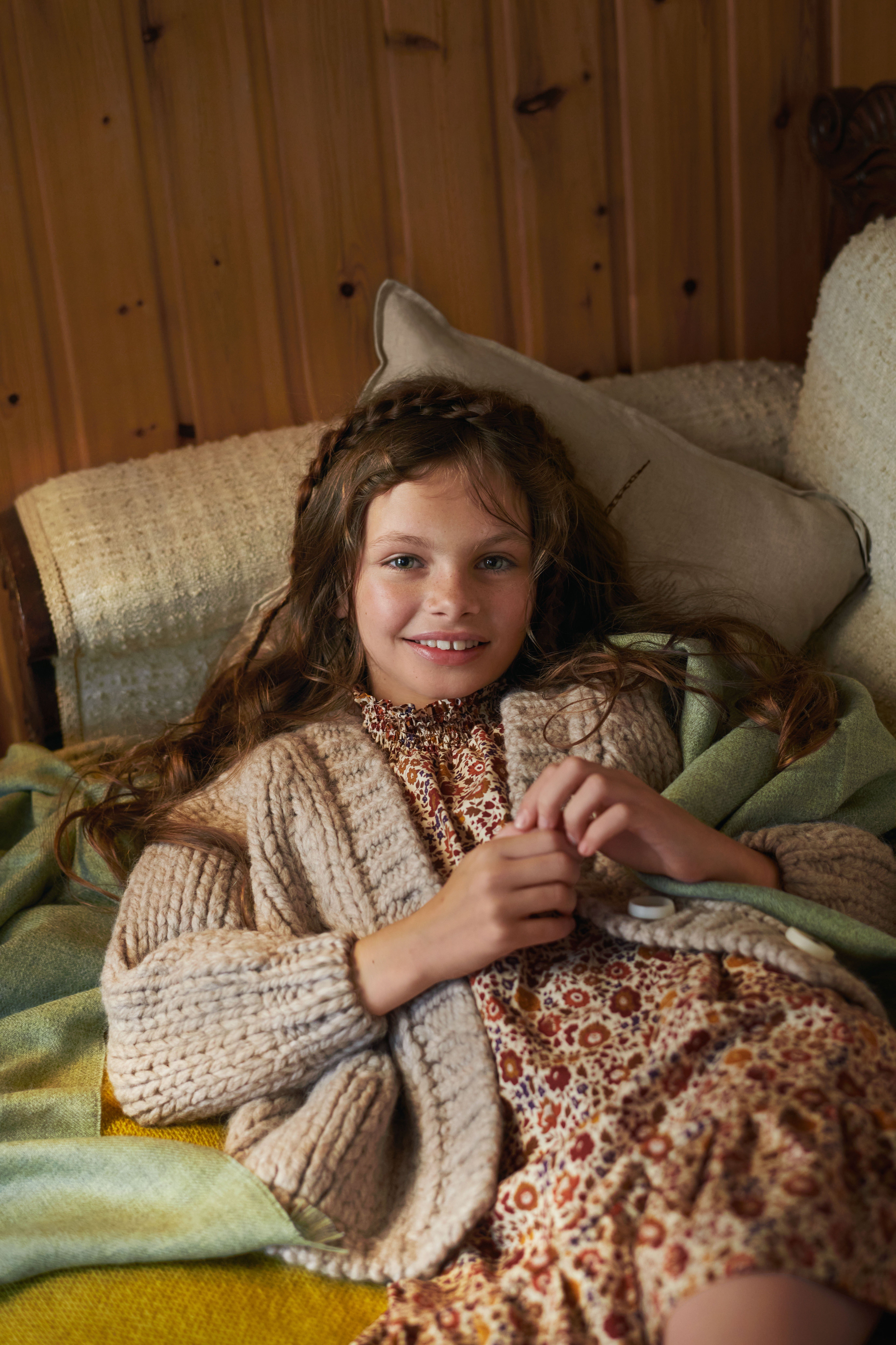 girl laying on a couch with a cozy warm sweater