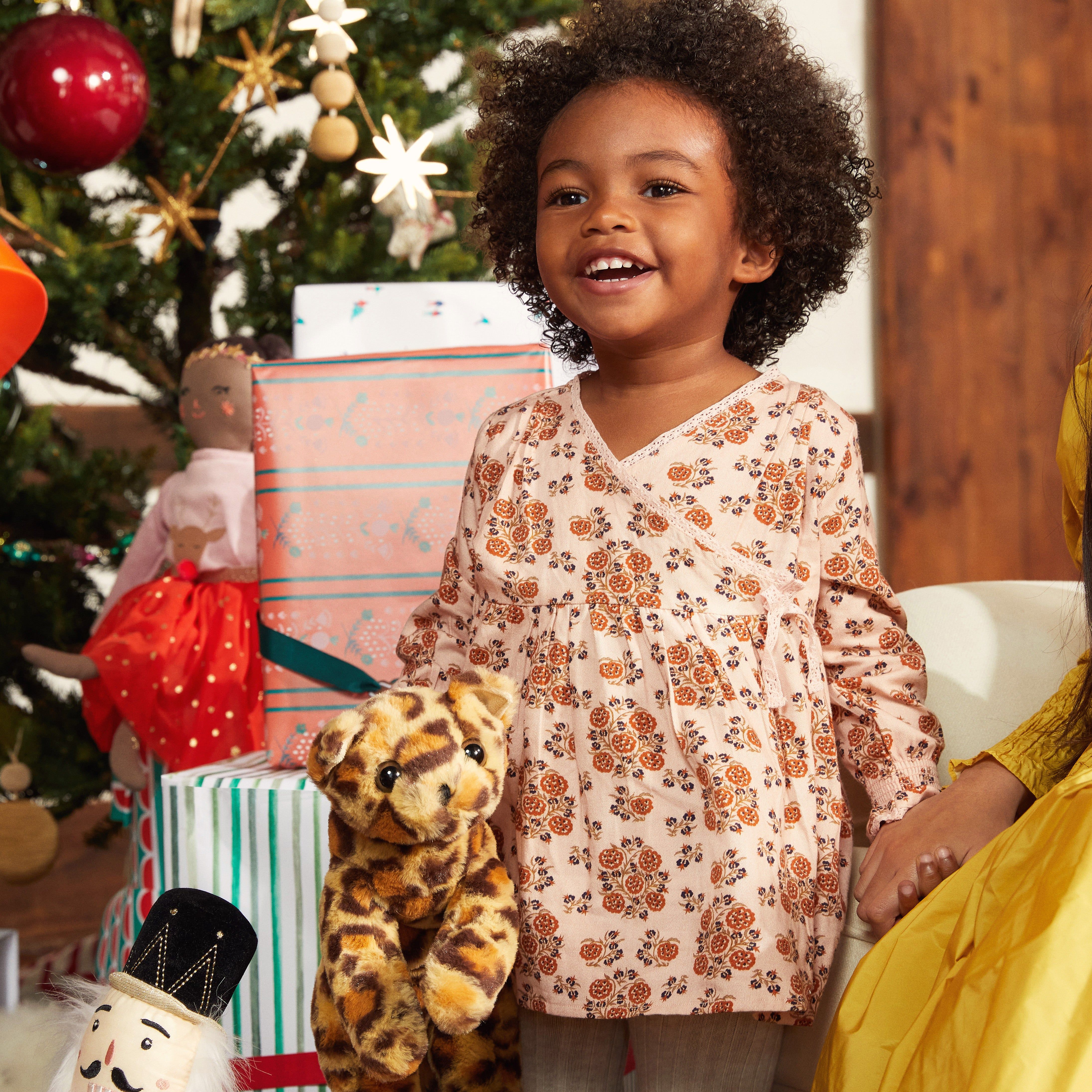 one year old girl opening presents at her first Christmas