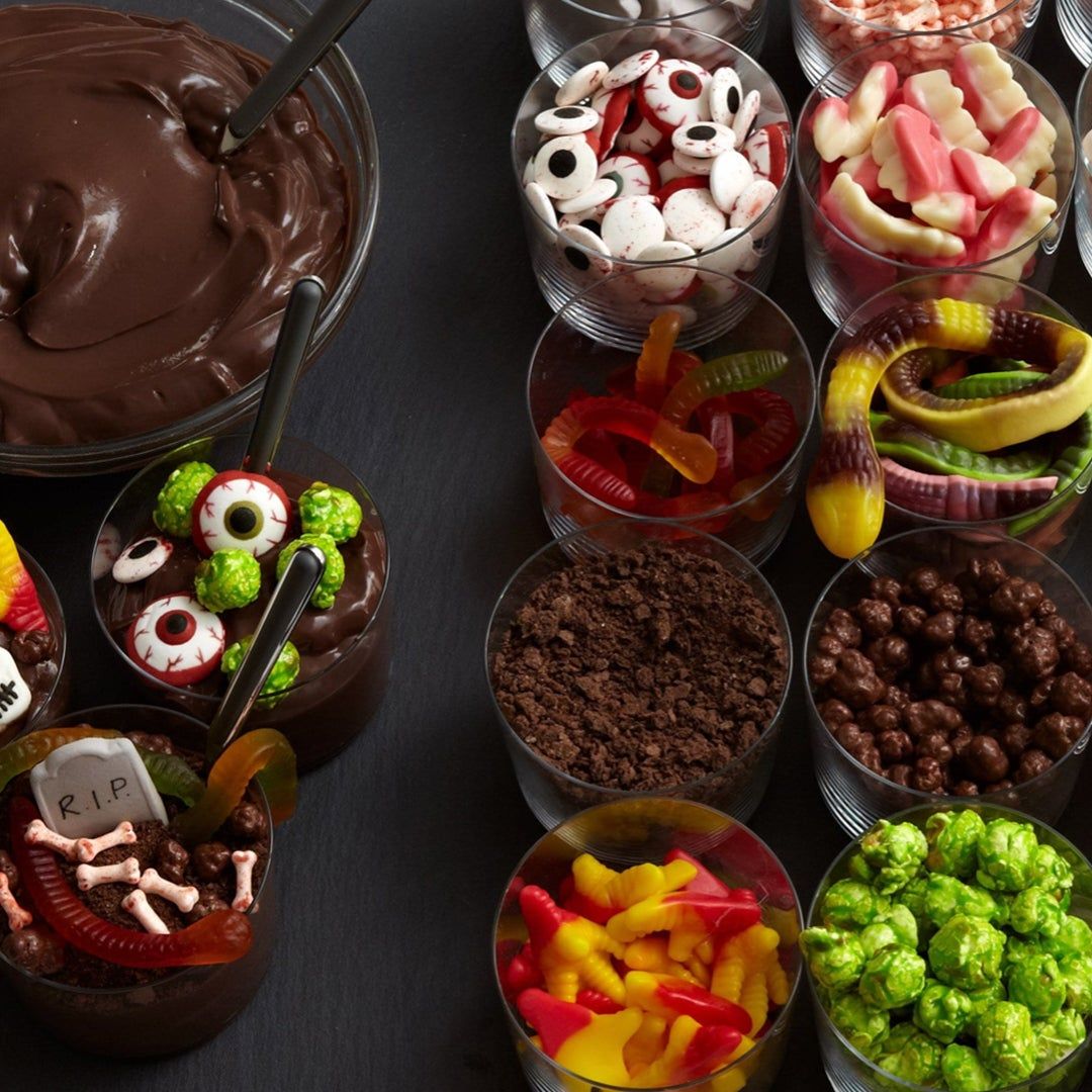 a dirt cake bar action with cups of creepy candies like gummy worms, eyes, and candy bones