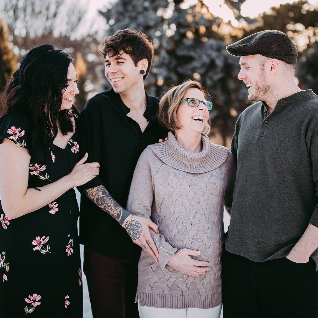 four adult children standing with their pregnant middle-aged mother