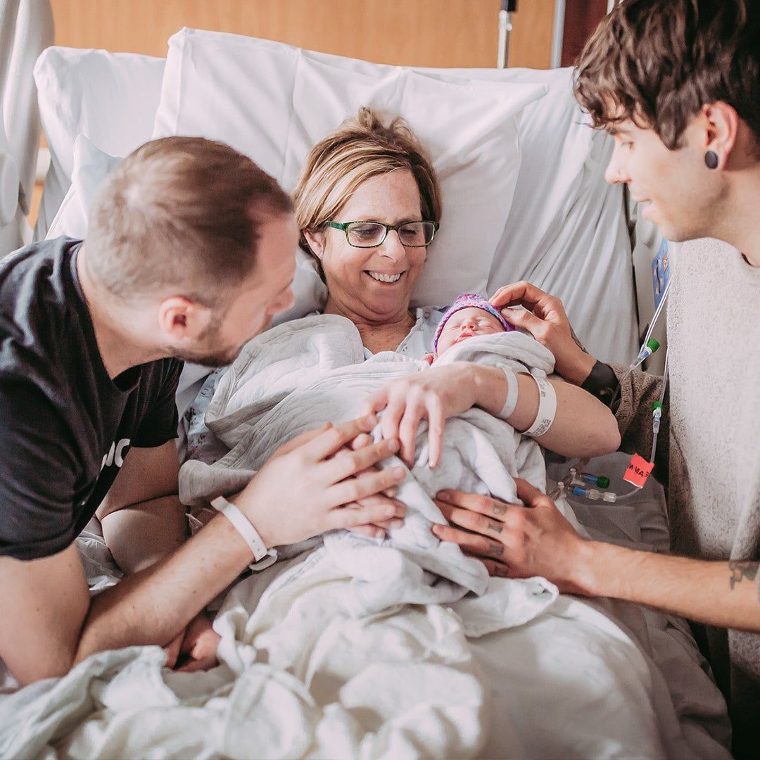 two men with a woman giving birth
