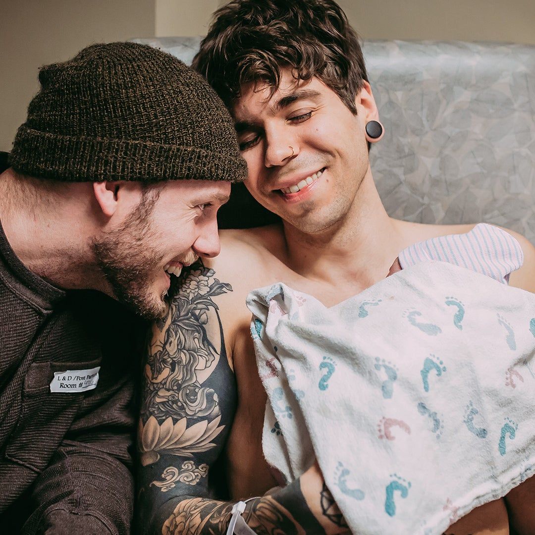 Two fathers holding their newborn baby