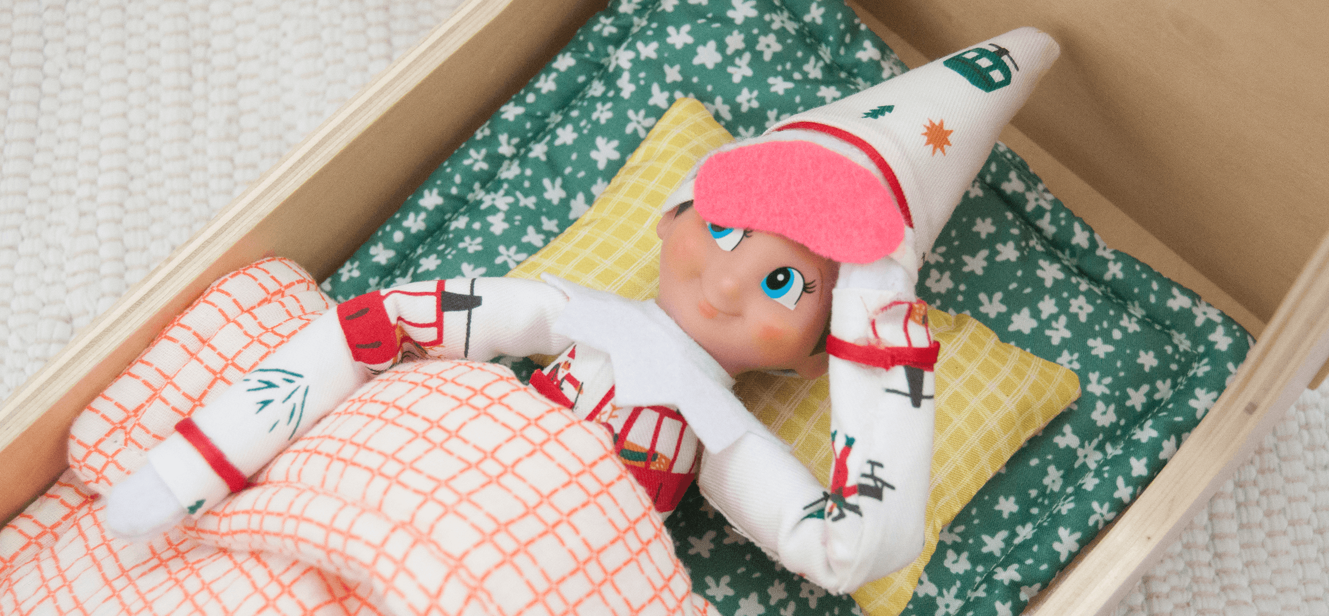 an Elf on the Shelf tucked into a cozy dollhouse bed