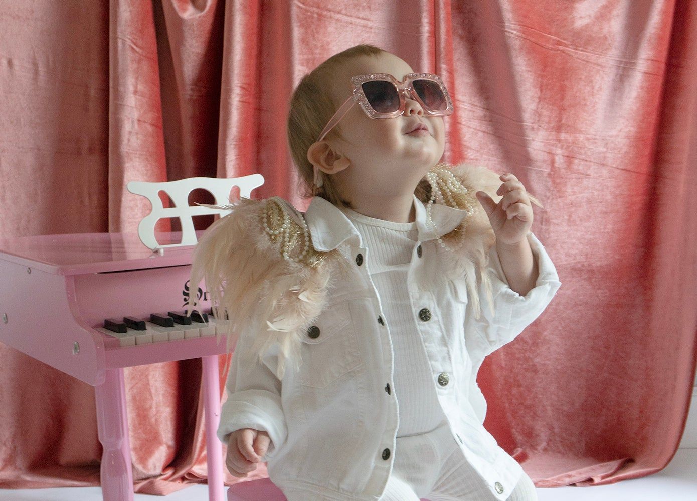 baby in glam sunglasses dressed as Elton John at a piano