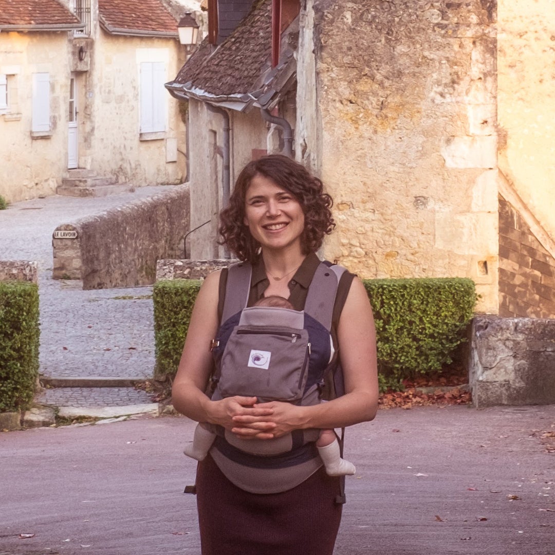 The author standing in front of a building with a baby in a baby bjorn.