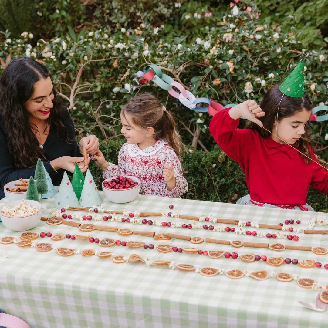 girls thread cranberries and popcorn on garlands for the holiday