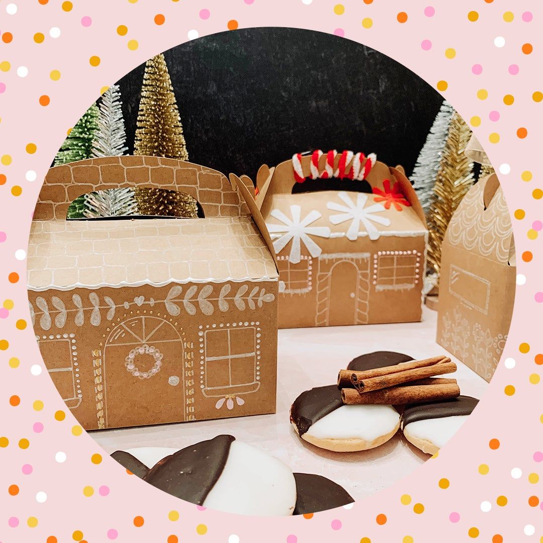 two cardboard gingerbread houses with black and white cookies and cinnamon sticks