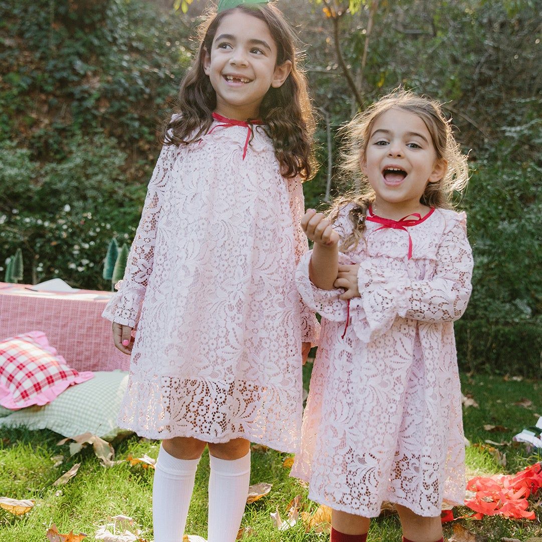 two girls in lace dresses and sparkly shoes outside in the sun