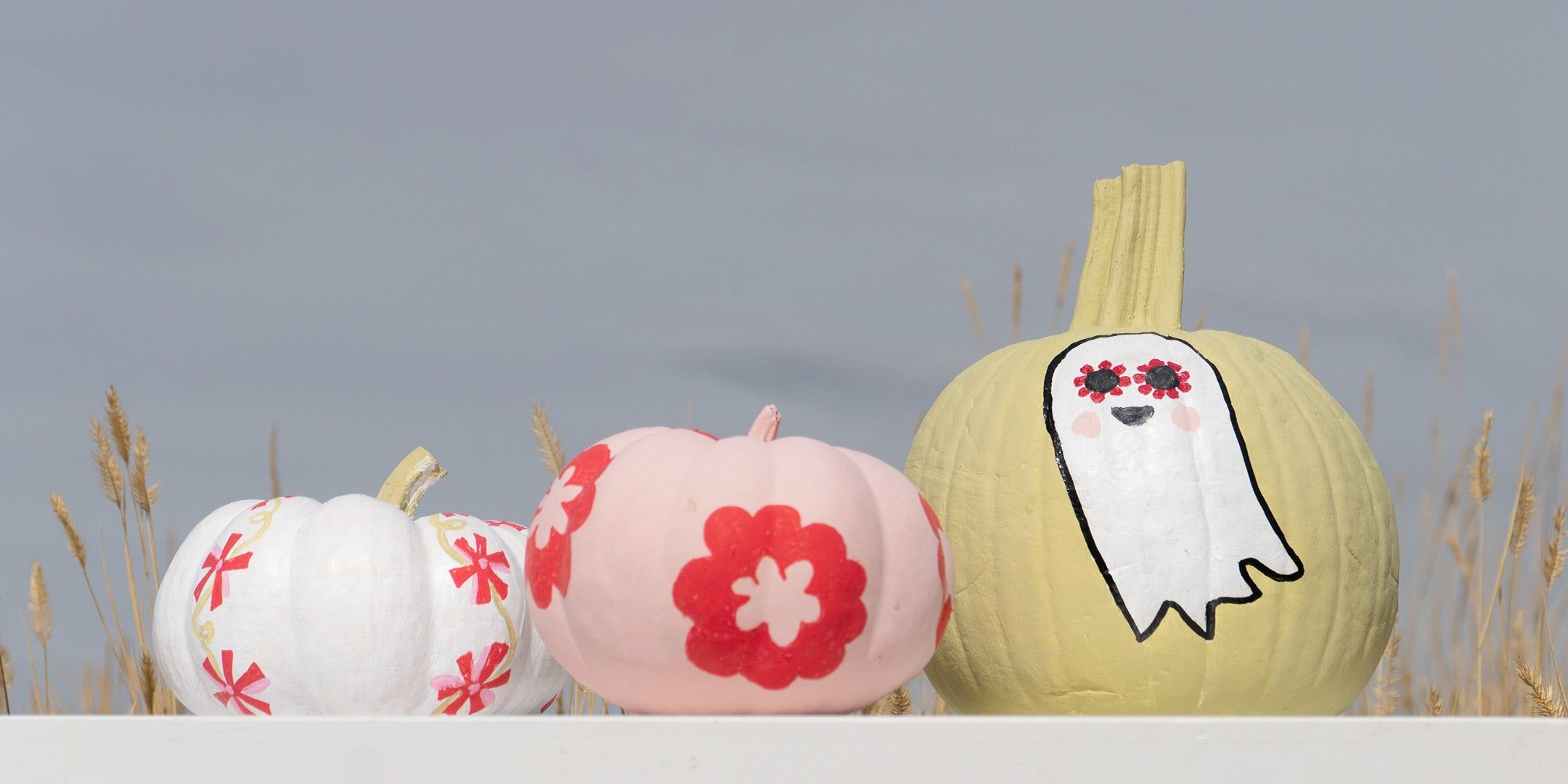 painted gourds of different shapes with a doll face, flowers, vote and blue and white stripe