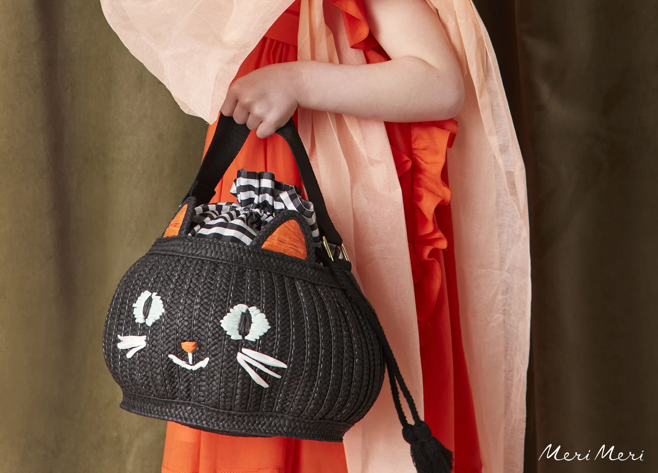 A child holding a black cat shaped basket.