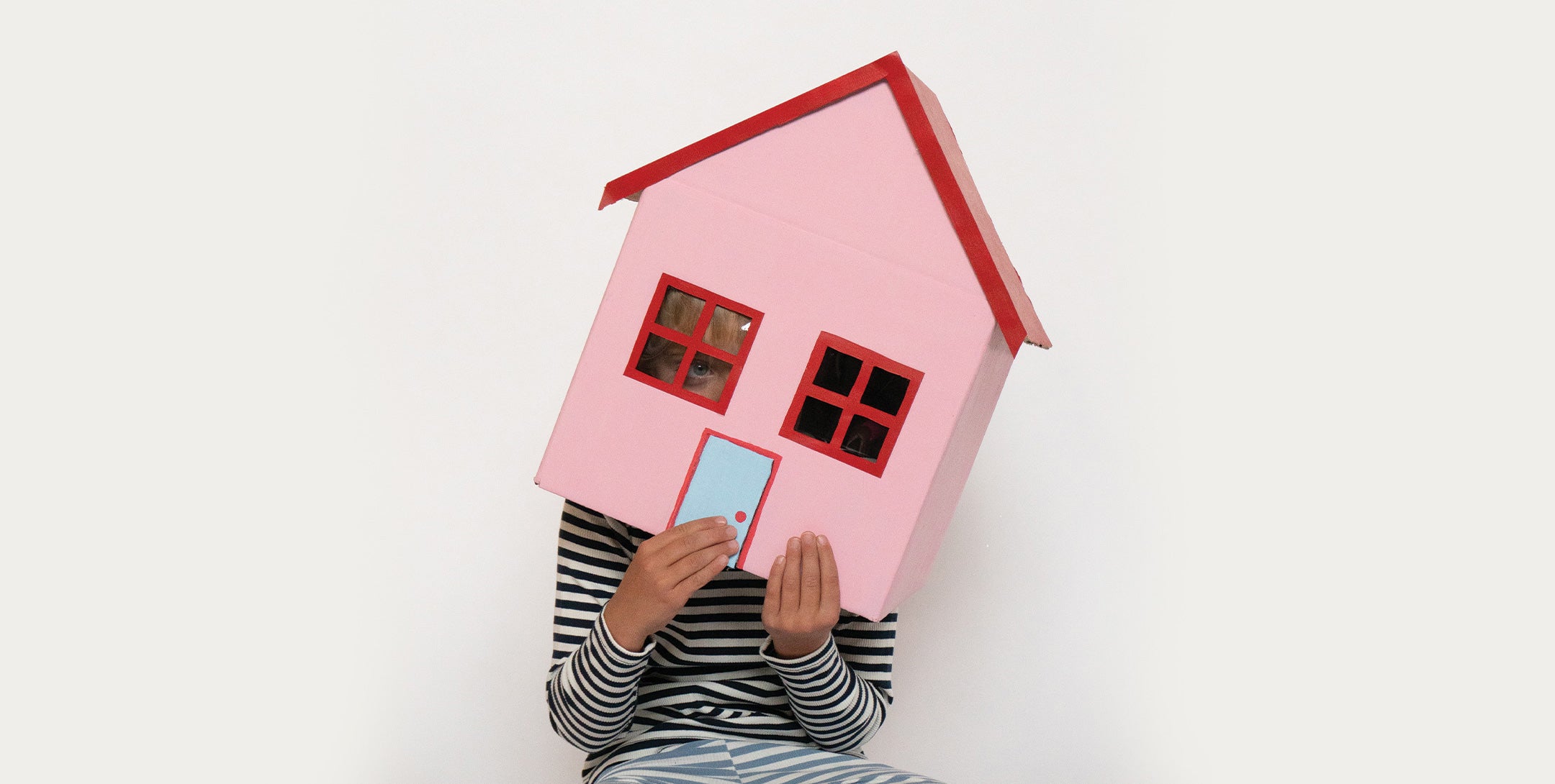A boy wears a cardboard house over his head as a costume