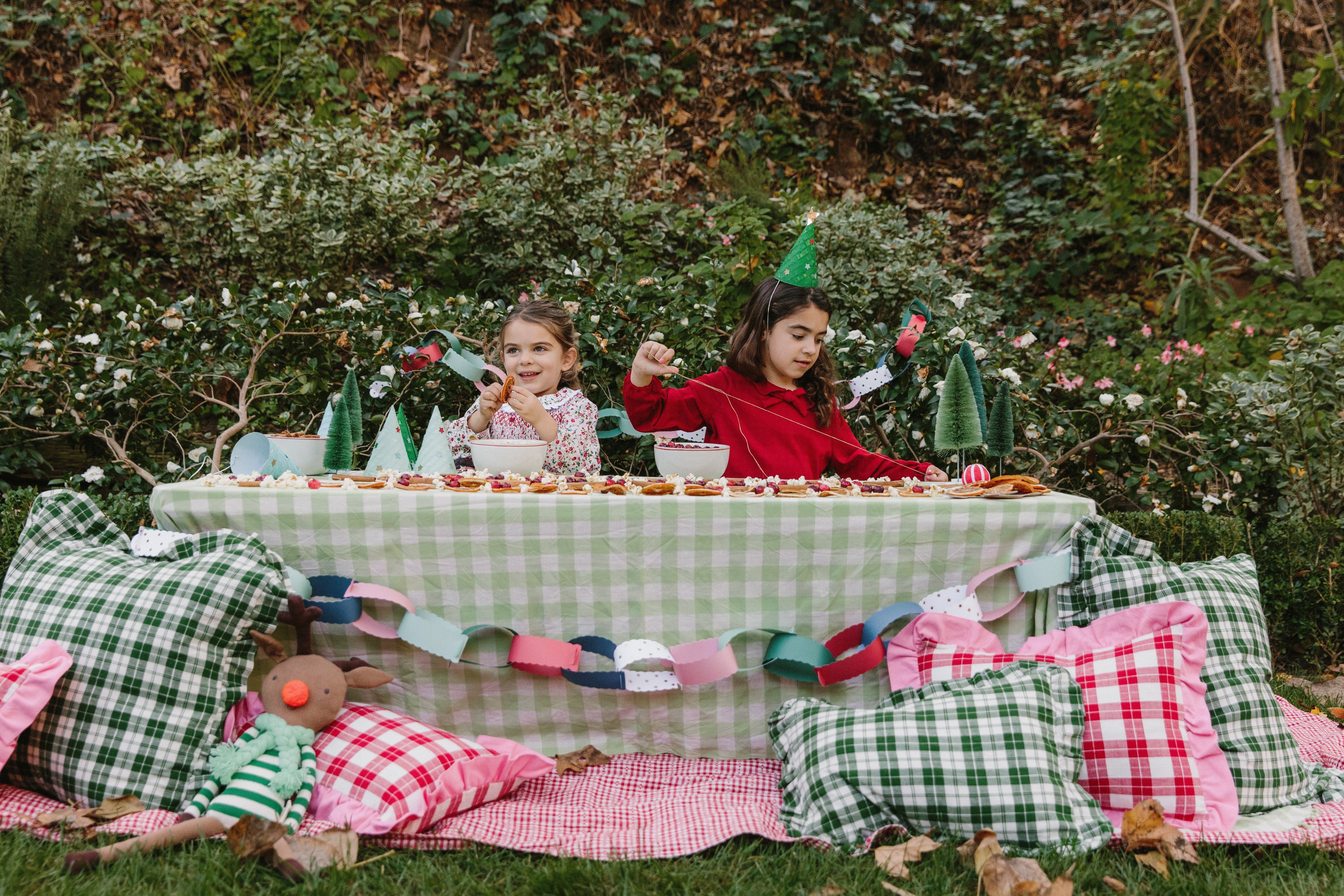 girls thread cranberries and popcorn on garlands for the holiday