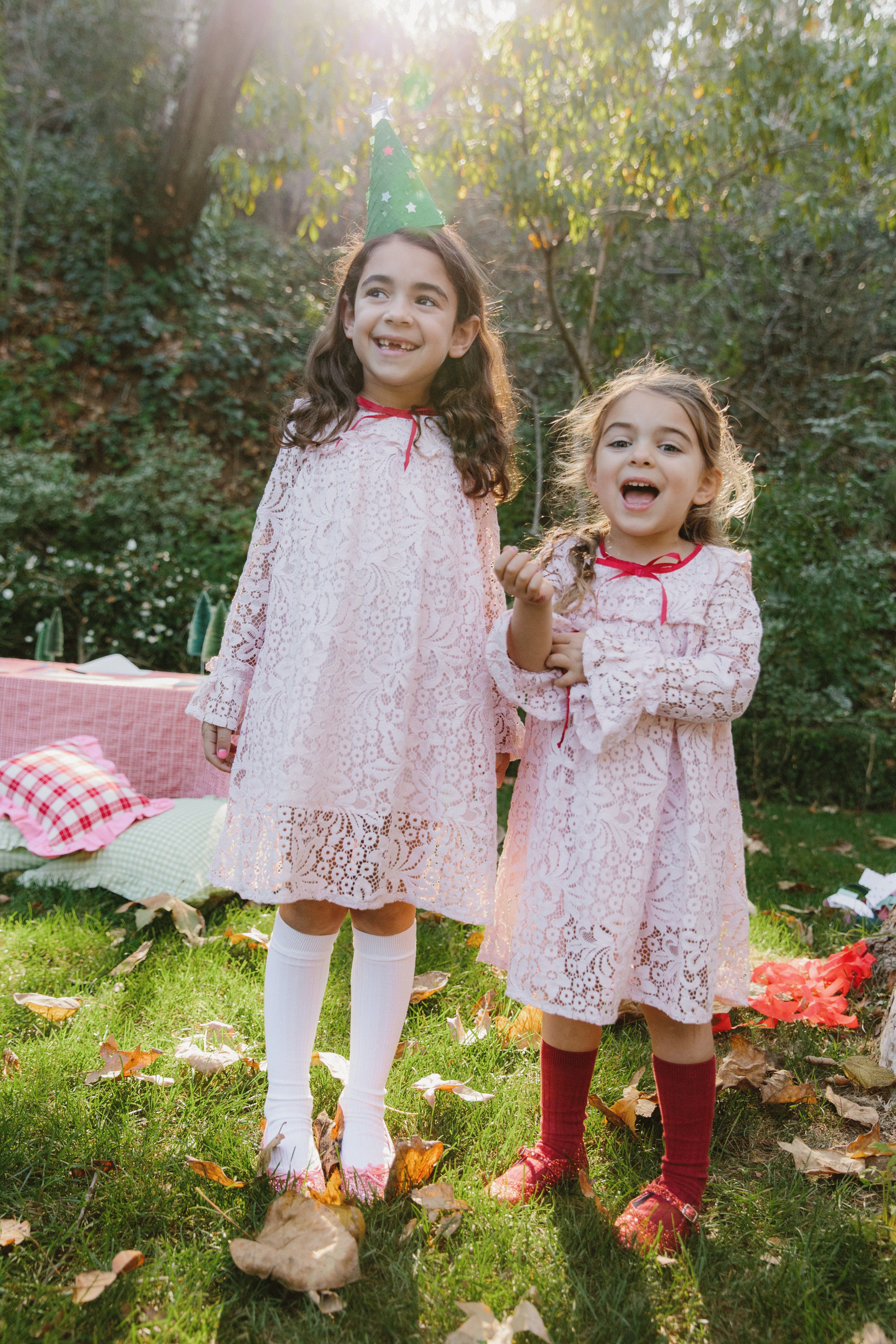 two girls in lace dresses and sparkly shoes outside in the sun