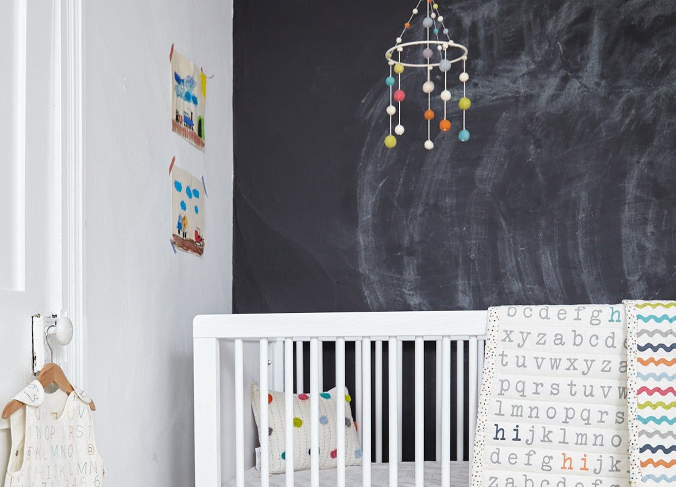 white crib in front of a chalkboard wall