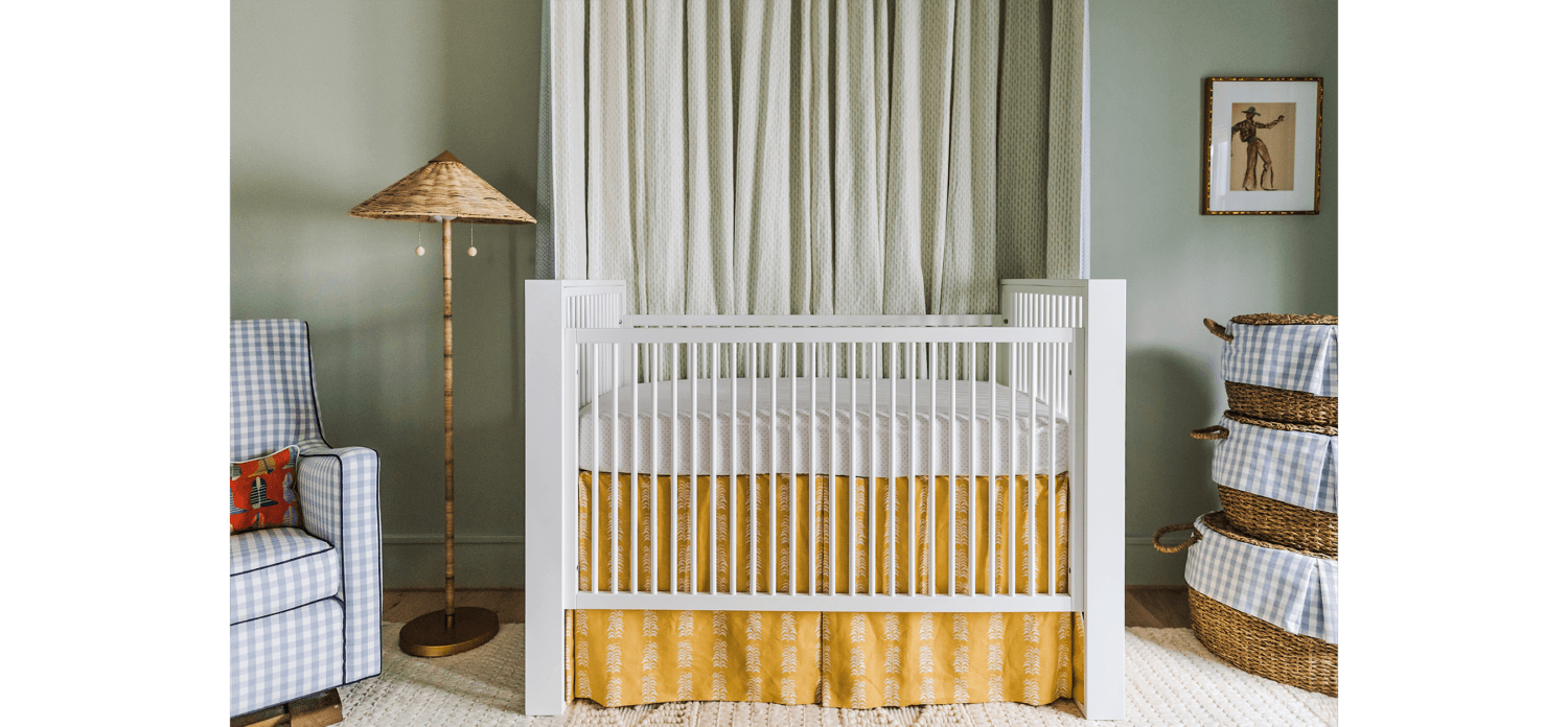green painted nursery with white crib and wicker lamp