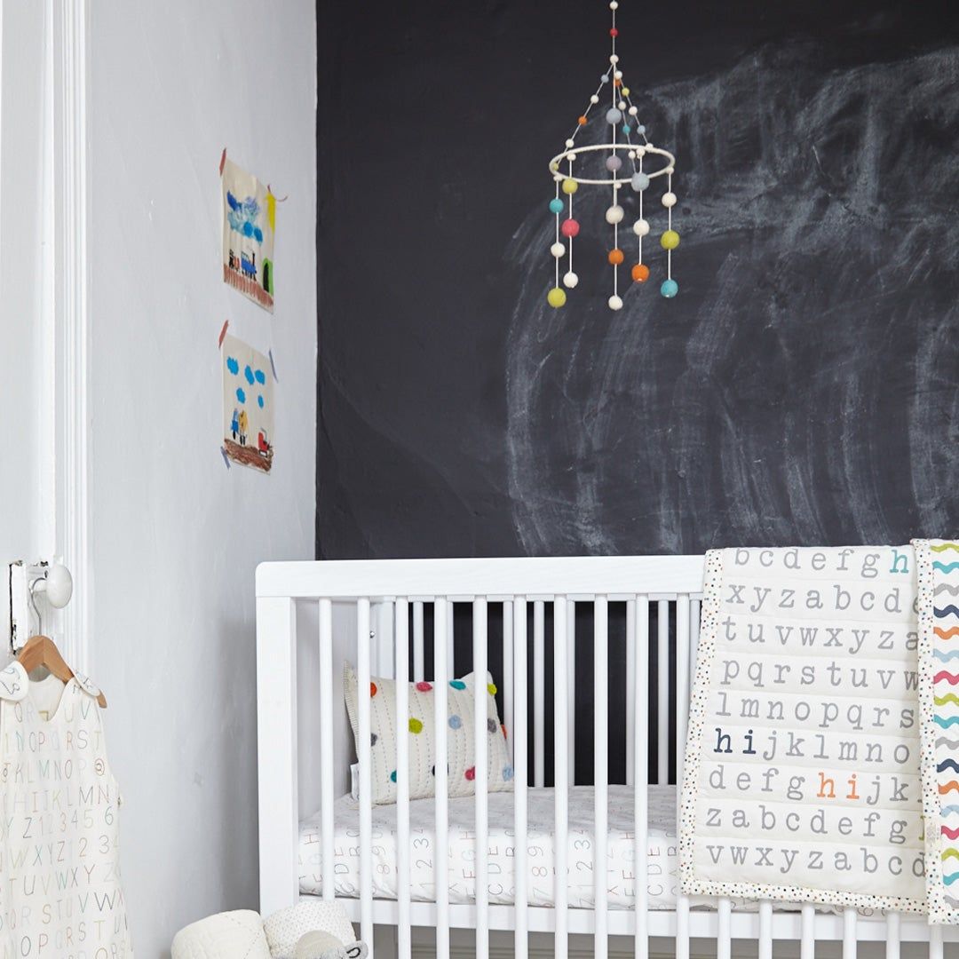 white crib in front of a chalkboard wall