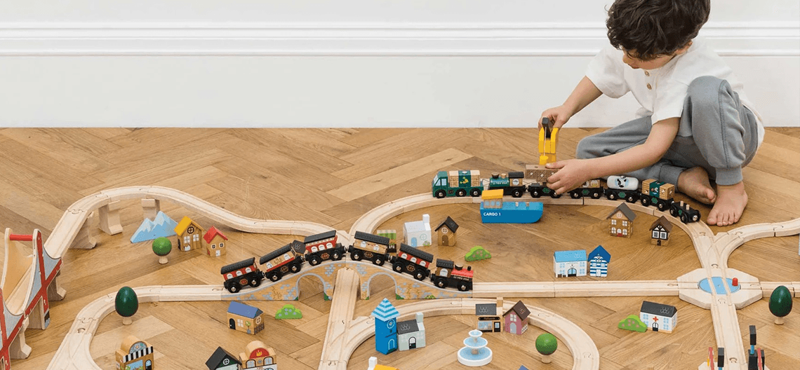 boy playing with Le Toy Van train track