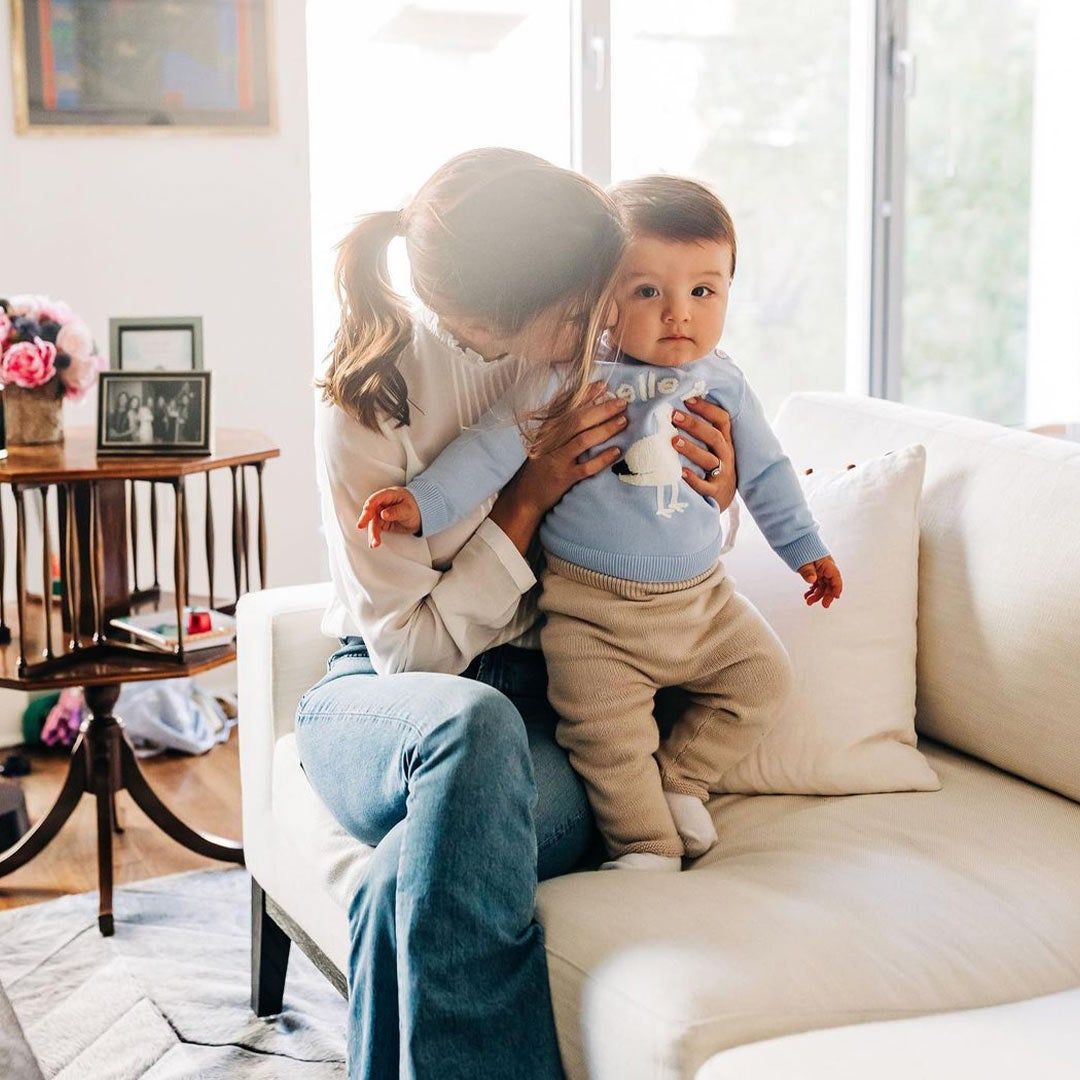 Marcella Kelson holding and kissing her baby son on the couch in her home