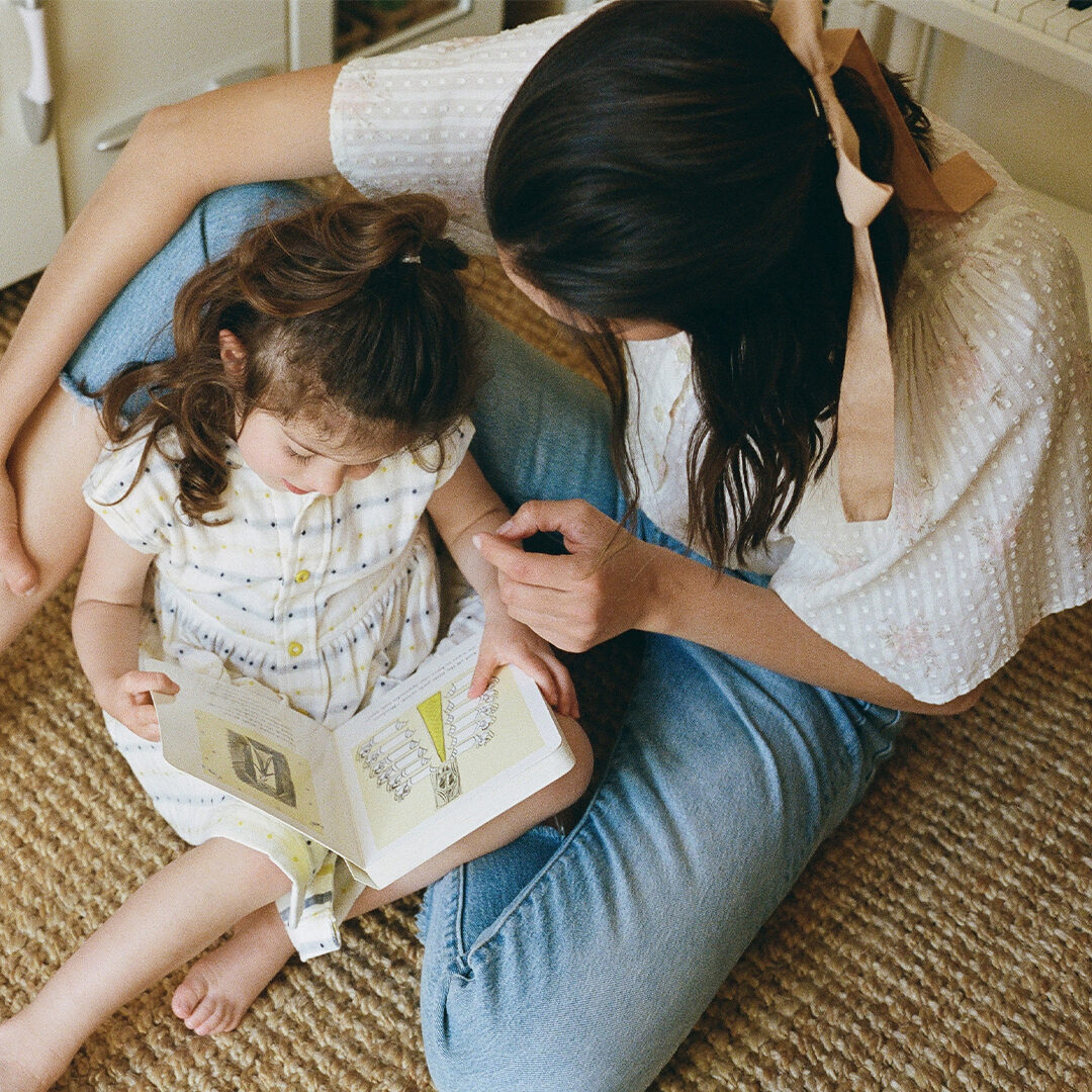 A mother and her daughter sitting and reading a book