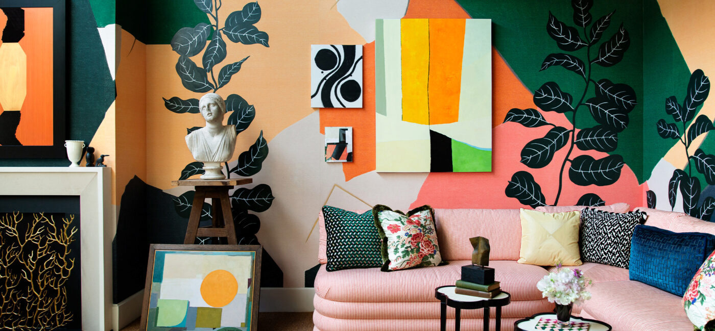 A beautifully decorated room with pink, yellow, and orange wallpaper, a bust on a stool, and a pink couch