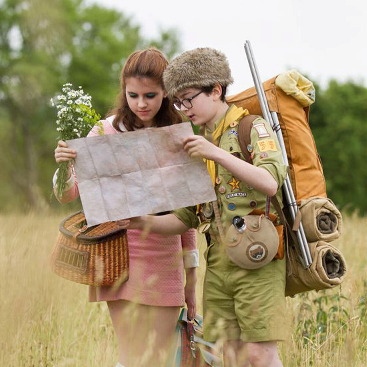 A boy and a girl in a field looking at a map