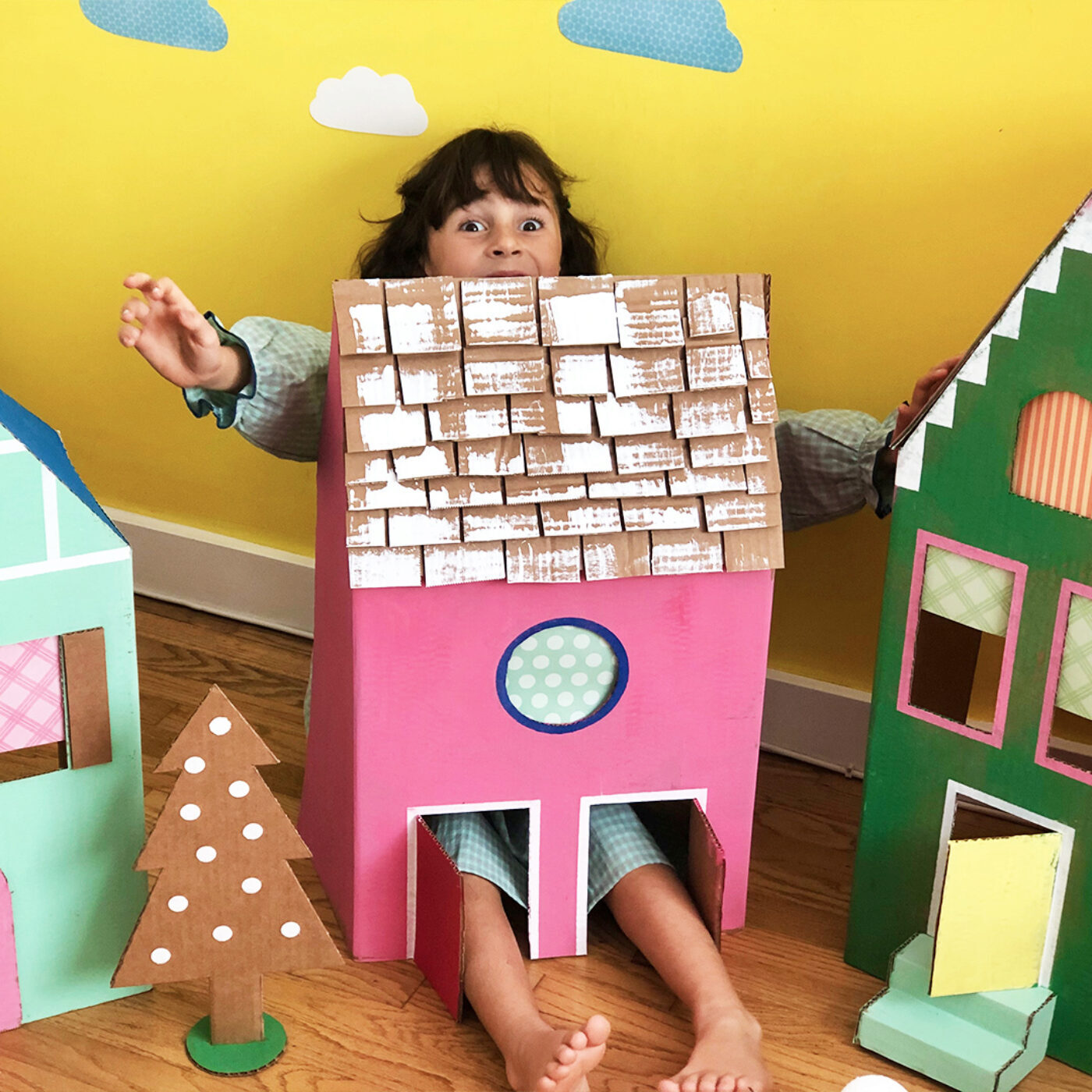 a little girl inside a colorful cardboard box house