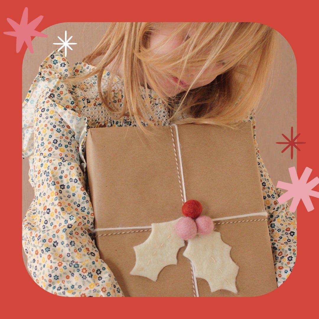 girl holding wrapped package with felt holly leaf adornment