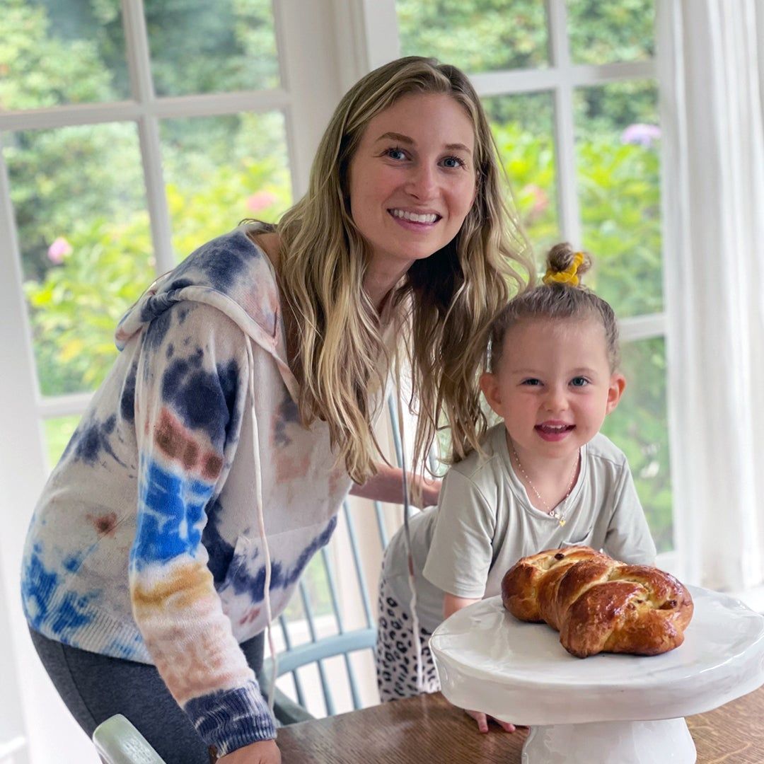 Molly Reiger and her daughter standing at a dining room table with challah bread 