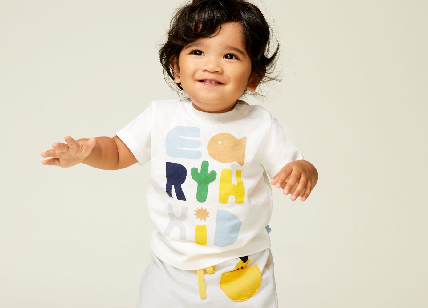 Little dark headed toddler with a white t-shirt and pants