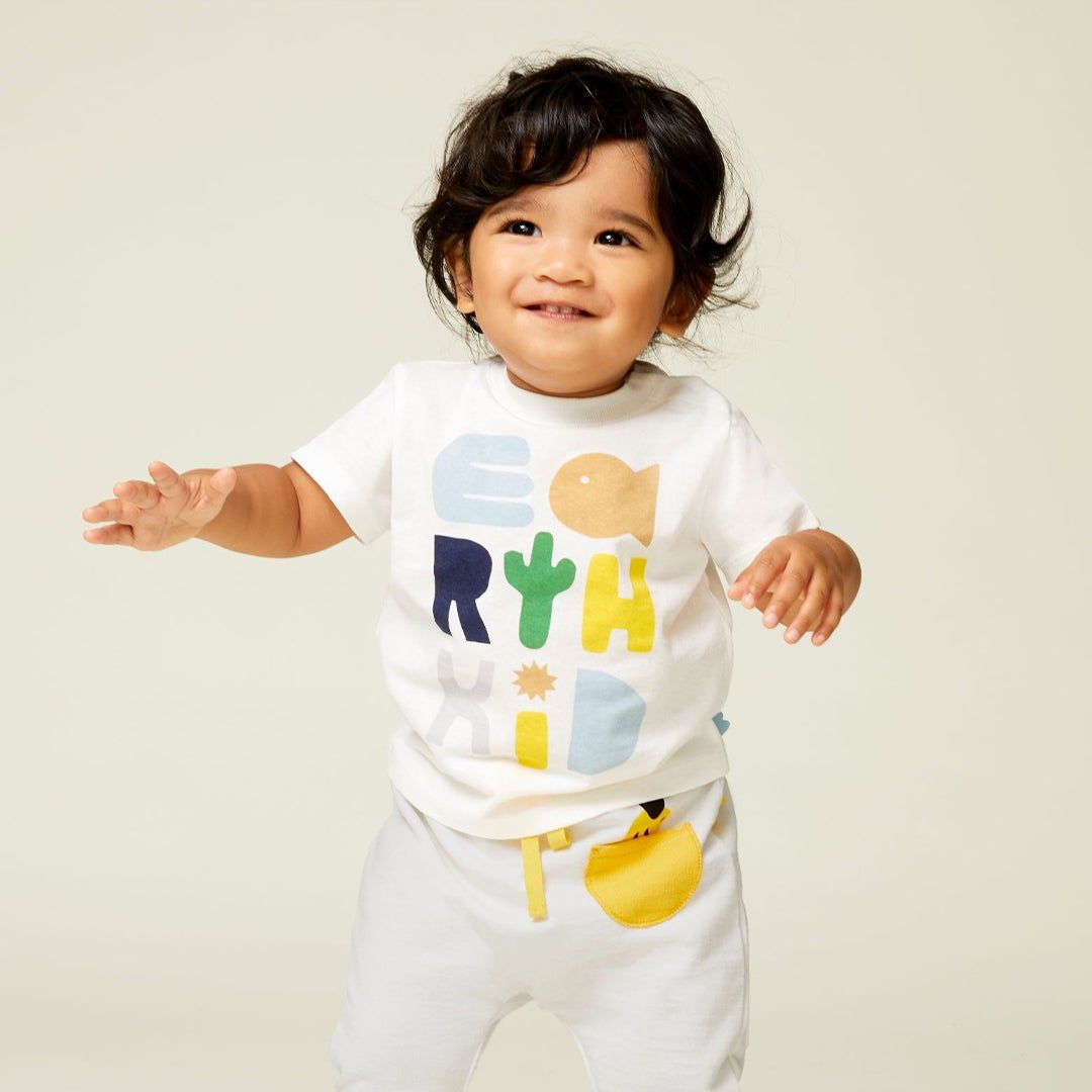 Little dark headed toddler with a white t-shirt and pants